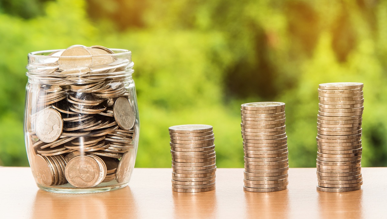 Money stacked and in a jar representing the saving of money due to lower energy costs from insulation.